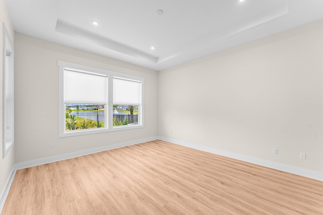 unfurnished room featuring recessed lighting, a raised ceiling, baseboards, and light wood finished floors