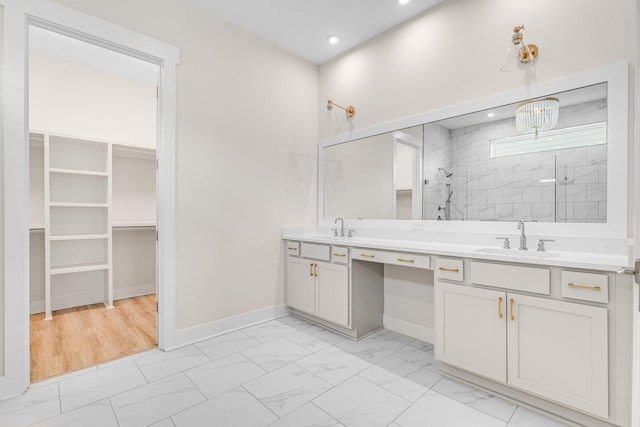 bathroom featuring a sink, marble finish floor, a walk in closet, and a shower stall