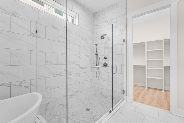 bathroom featuring a soaking tub, a shower stall, and a walk in closet