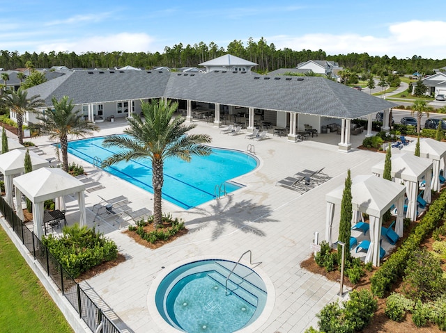 community pool featuring a patio, a community hot tub, fence, a gazebo, and a residential view