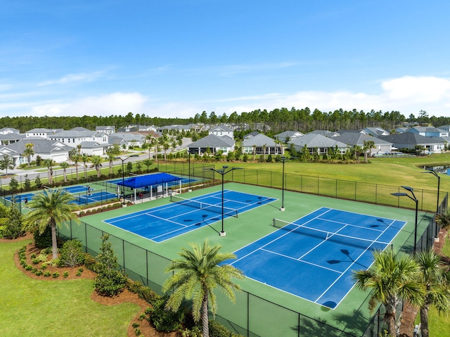 view of tennis court with a yard, fence, and a residential view