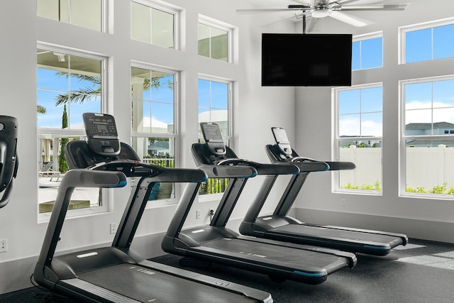 exercise room featuring ceiling fan and a towering ceiling