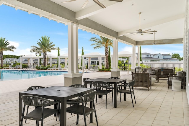 view of patio / terrace with outdoor dining area, ceiling fan, fence, a community pool, and a residential view