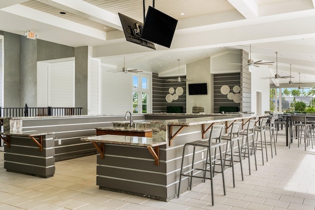 bar featuring a wealth of natural light, a sink, and beam ceiling