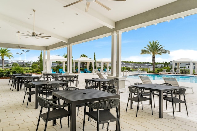 view of patio / terrace featuring a community pool, a ceiling fan, and outdoor dining space