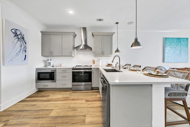 kitchen featuring built in microwave, wall chimney exhaust hood, sink, a breakfast bar area, and stainless steel range with electric stovetop