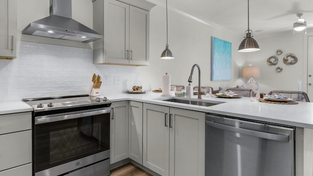 kitchen with gray cabinets, appliances with stainless steel finishes, sink, and wall chimney range hood