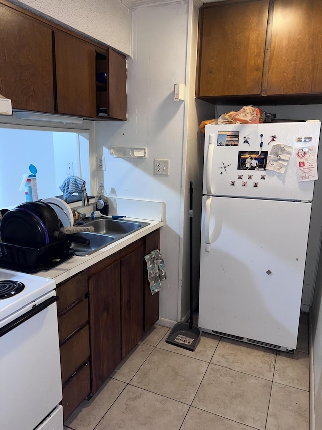 kitchen featuring dark brown cabinets, light tile patterned flooring, and white fridge