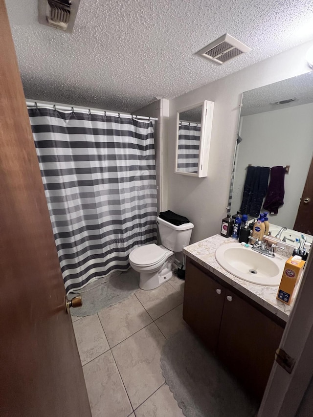 bathroom featuring tile patterned flooring, vanity, a textured ceiling, and toilet