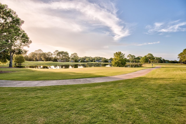 surrounding community with a water view and a lawn