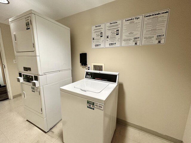 shared laundry area with stacked washer / dryer, baseboards, and light tile patterned floors