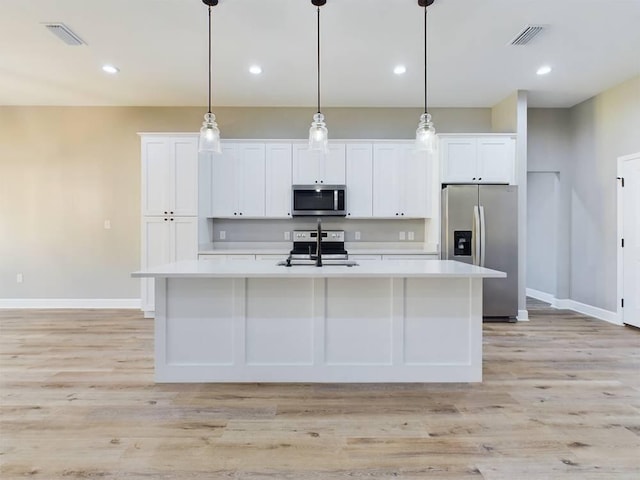 kitchen with white cabinets, stainless steel appliances, light hardwood / wood-style flooring, and an island with sink