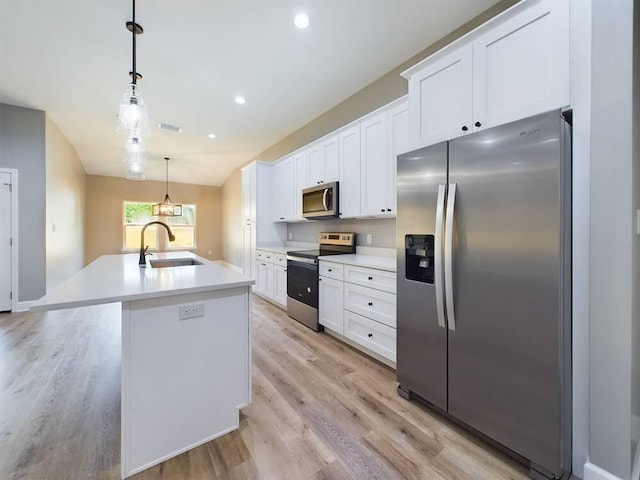 kitchen featuring stainless steel appliances, a sink, white cabinetry, light wood finished floors, and an island with sink