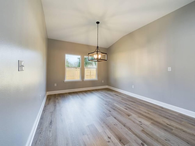 unfurnished dining area with lofted ceiling, a chandelier, and wood-type flooring