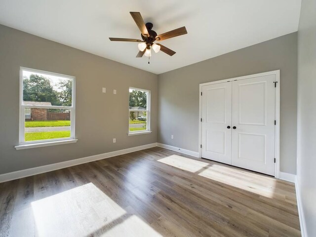 empty room with a wealth of natural light, hardwood / wood-style flooring, and ceiling fan