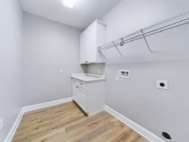 clothes washing area featuring hookup for an electric dryer, light hardwood / wood-style floors, hookup for a washing machine, and cabinets