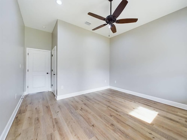 unfurnished room with a ceiling fan, light wood-type flooring, visible vents, and baseboards