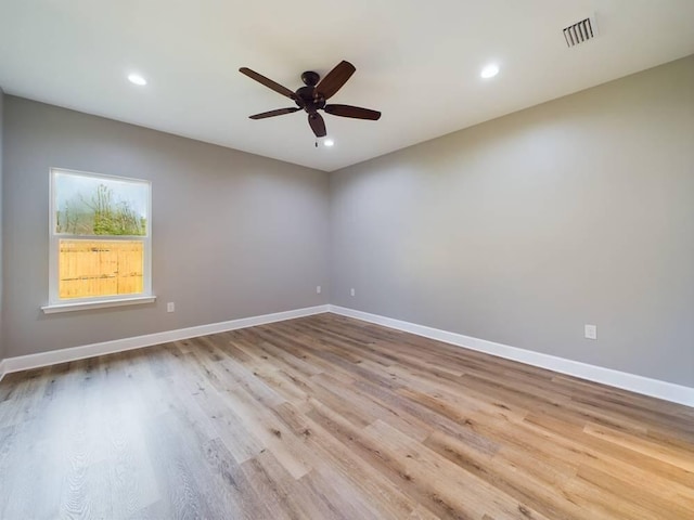 spare room with wood finished floors, visible vents, and baseboards