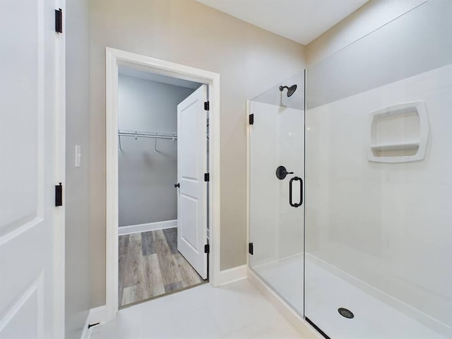 bathroom featuring a stall shower, a spacious closet, and baseboards