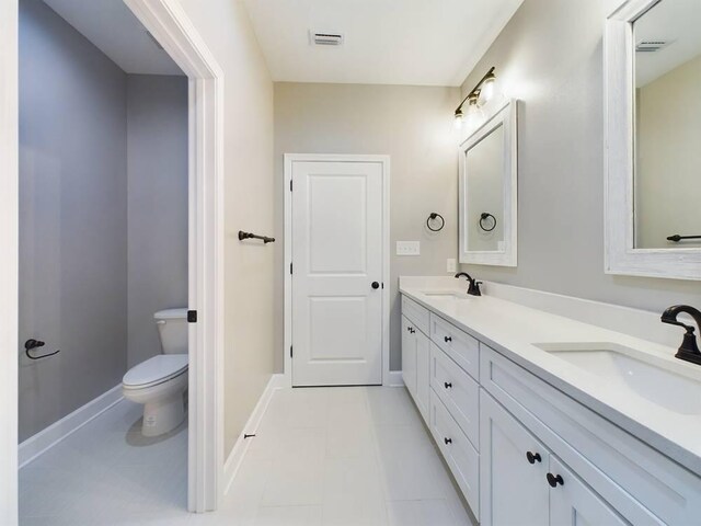 bathroom with tile patterned floors, double sink vanity, and toilet