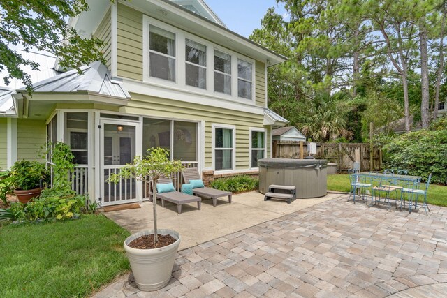 rear view of property featuring a hot tub and a patio area