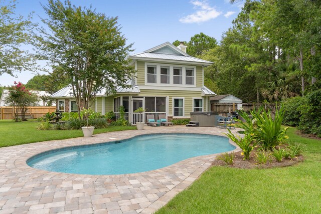 back of house featuring a sunroom, a patio area, a lawn, and a fenced in pool