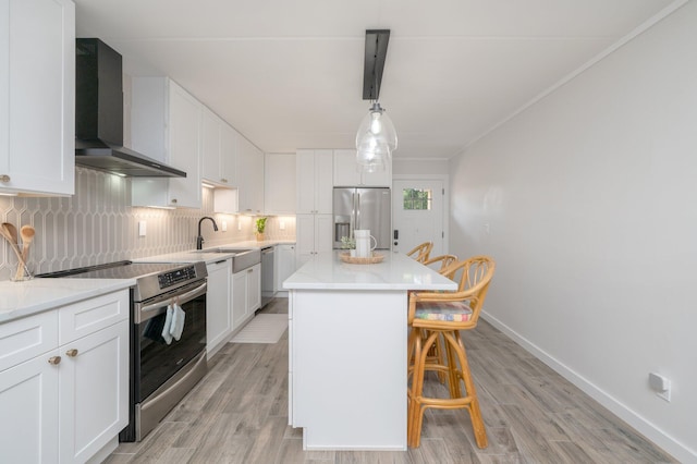 kitchen with white cabinets, appliances with stainless steel finishes, wall chimney exhaust hood, and a kitchen island