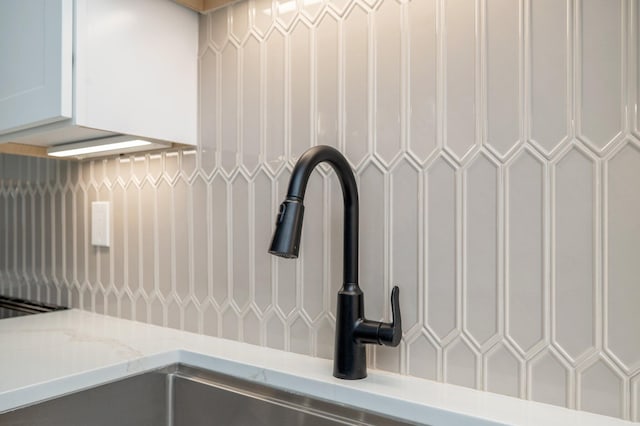 interior details featuring white cabinetry and light stone counters