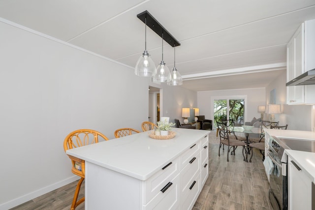 kitchen with white cabinetry, light hardwood / wood-style floors, electric range, a kitchen breakfast bar, and a center island