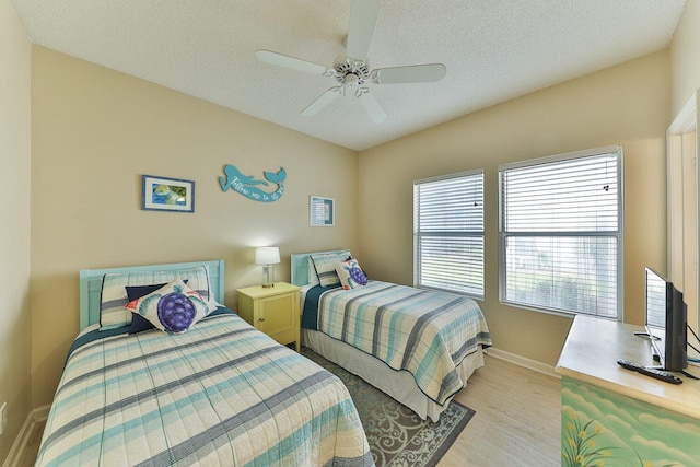 bedroom with ceiling fan, vaulted ceiling, a textured ceiling, and light wood-type flooring