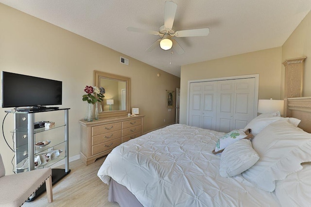 bedroom featuring vaulted ceiling, ceiling fan, light hardwood / wood-style floors, and a closet