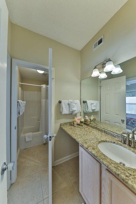 bathroom featuring tile patterned floors, shower / tub combo, vanity, and a textured ceiling