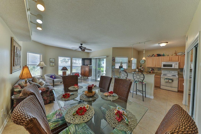 dining space with light tile patterned floors, track lighting, a textured ceiling, and ceiling fan