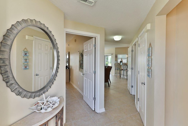 corridor featuring light tile patterned flooring and a textured ceiling