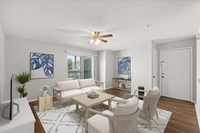 living room with a textured ceiling, ceiling fan, and dark hardwood / wood-style flooring