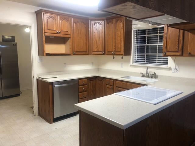 kitchen with kitchen peninsula, appliances with stainless steel finishes, light tile patterned floors, and sink