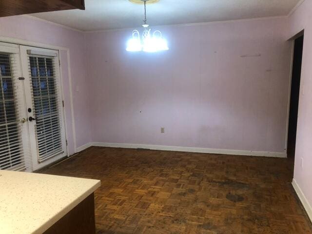 empty room featuring a notable chandelier, french doors, and parquet flooring