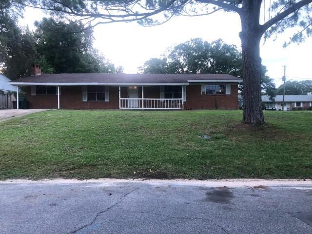 ranch-style house featuring a carport, a porch, a front yard, and driveway