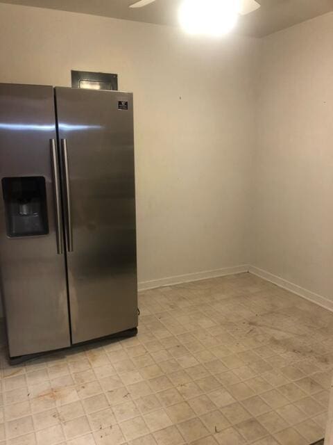 kitchen featuring ceiling fan, light floors, stainless steel fridge, and baseboards