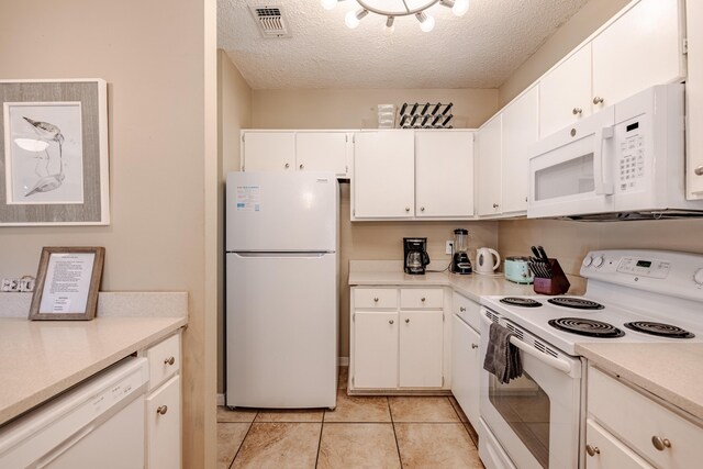 kitchen featuring light tile patterned floors, a textured ceiling, white cabinets, and white appliances