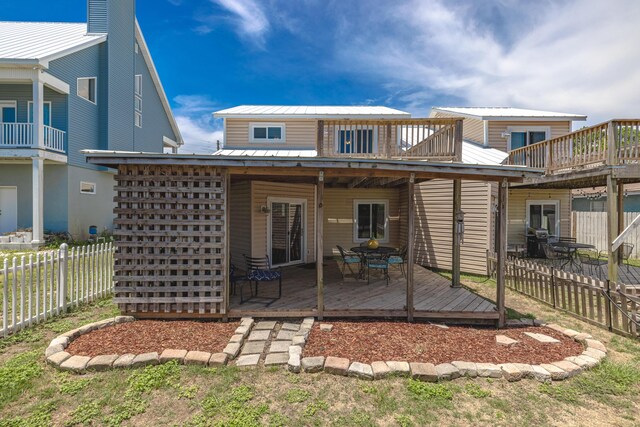 back of house featuring a balcony and a wooden deck