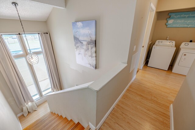 hallway featuring separate washer and dryer, a textured ceiling, and light hardwood / wood-style floors