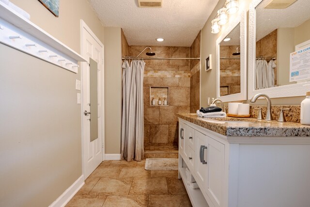 bathroom with tile patterned flooring, vanity, and a textured ceiling