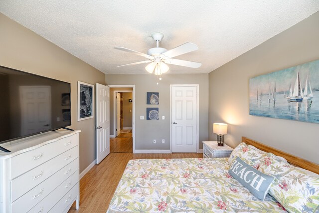 bedroom featuring light hardwood / wood-style floors, a textured ceiling, and ceiling fan