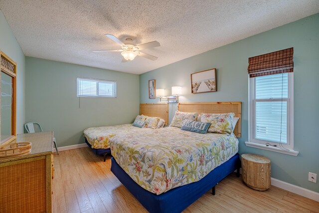 bedroom with light hardwood / wood-style flooring, a textured ceiling, and ceiling fan