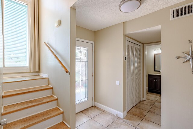 entryway with light tile patterned flooring, a textured ceiling, and a healthy amount of sunlight