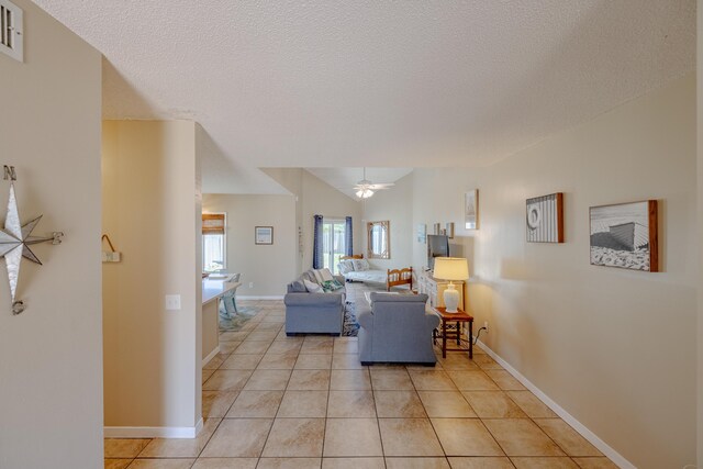 tiled living room with a textured ceiling and ceiling fan