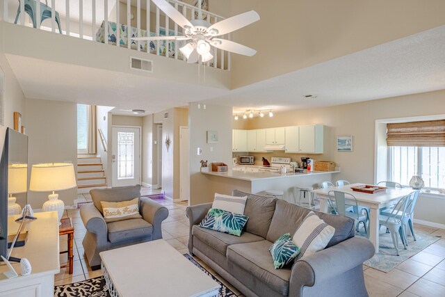 living room featuring a high ceiling, ceiling fan, track lighting, and light tile patterned floors