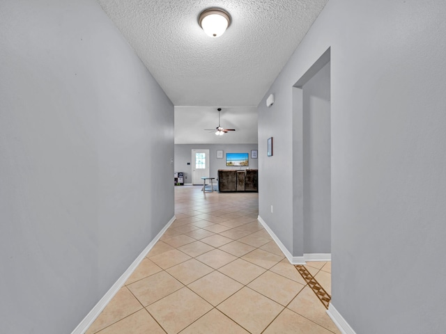 corridor featuring light tile patterned floors and a textured ceiling