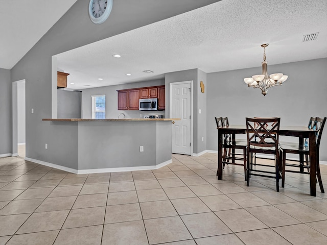 dining area with an inviting chandelier, a textured ceiling, light tile patterned floors, and vaulted ceiling